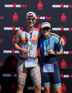 a triathlon couple who is standing in front of an ironman race backdrop