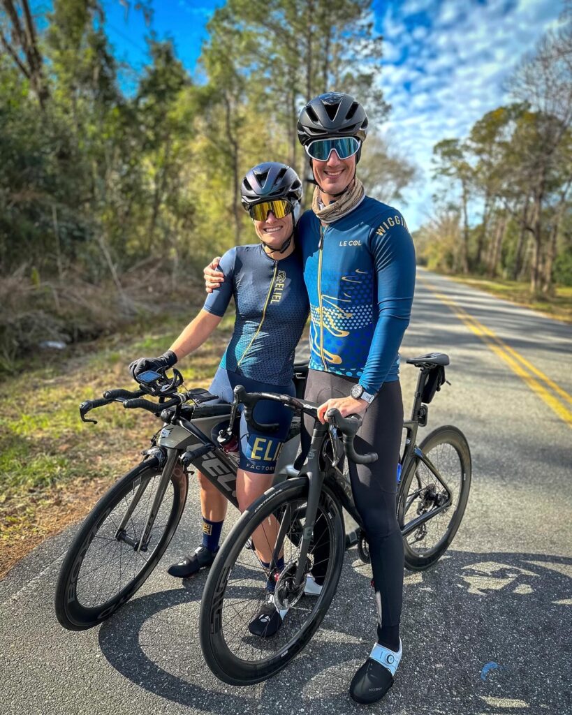 A female and male triathlete smiling while riding bikes
