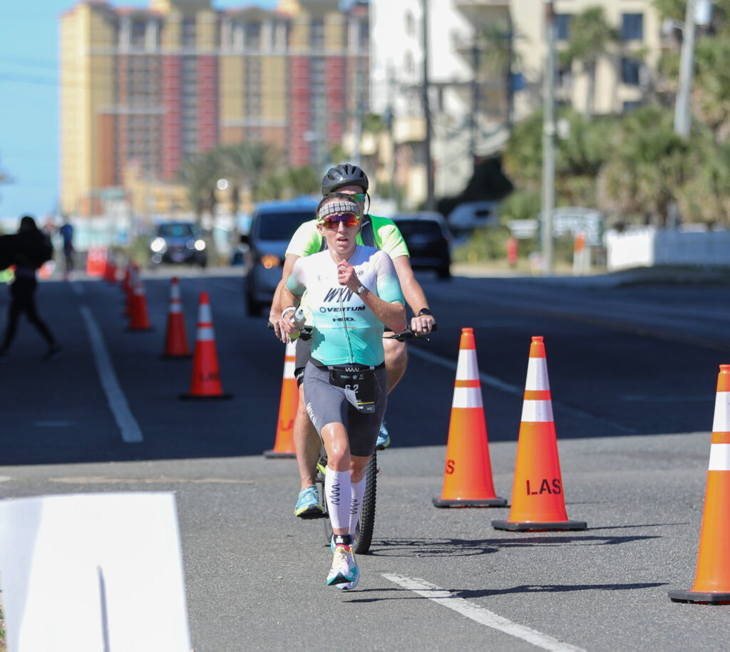 A female triathlete running in an Ironman triathlon.