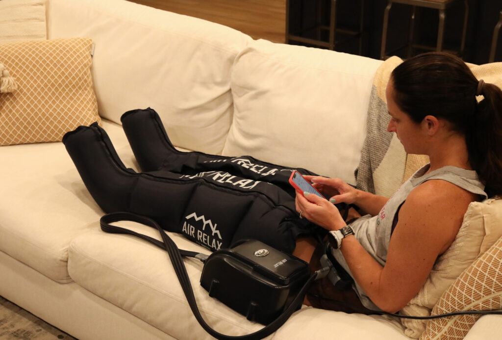 A woman looking on her phone while wearing recovery boots.