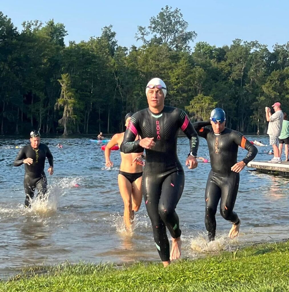 A female triathlete in a wetsuit exiting the swim at a triathlon