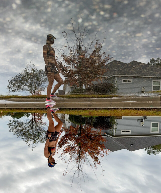 A female runner gazing into a pond with her reflection